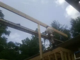 Carpenter setting a ridge beam over a new addition frame — Ice Dam Removal by Roofing Brothers in Slayden