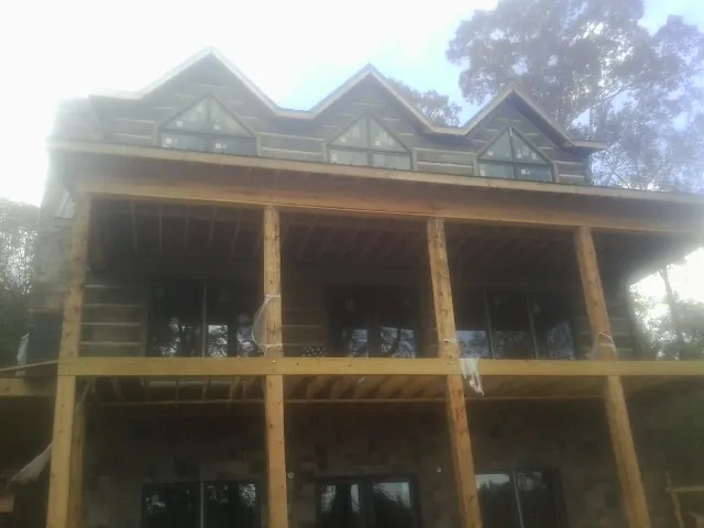 Dormers and porch framing on a large log home under construction — Roof Coating work by our crew in Slayden