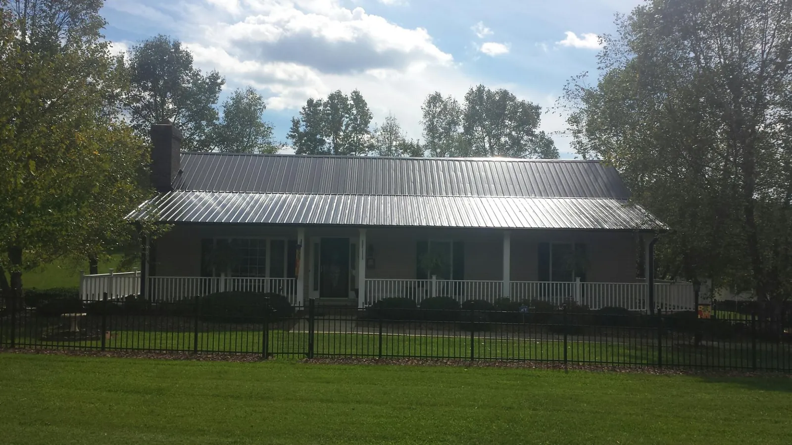 Gray metal roof on a brick ranch with a full width front porch — Gutter Guard Installation work by our crew in Slayden