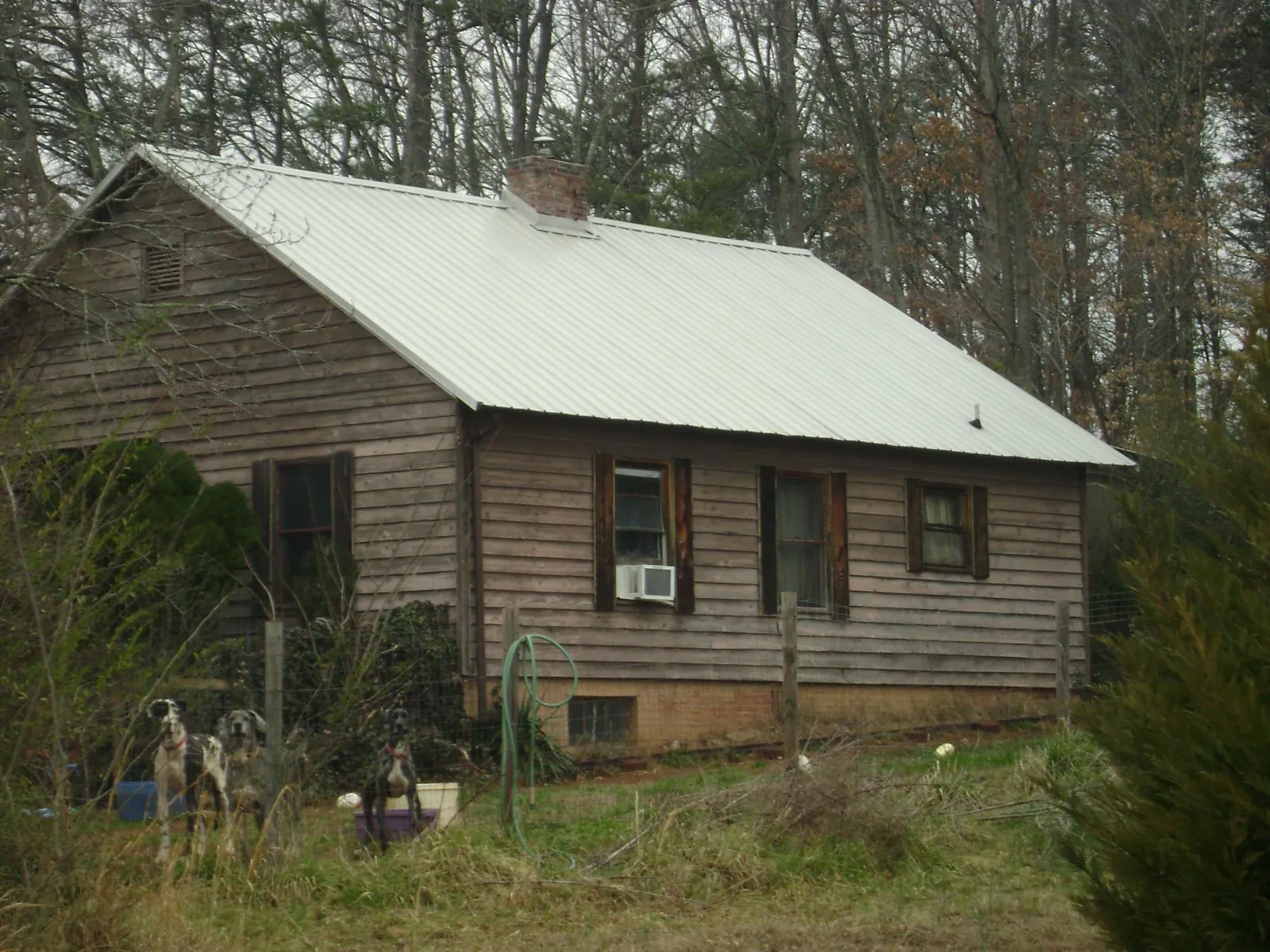 White metal roof on an old wood sided farmhouse, from a Metal Roof Installation job in Slayden