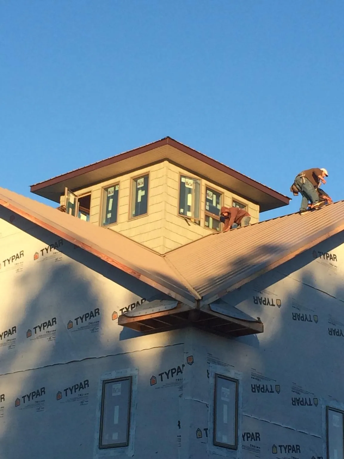 Roofers working around a rooftop cupola on a new metal roof at sunset — Roof Waterproofing in Slayden by Roofing Brothers